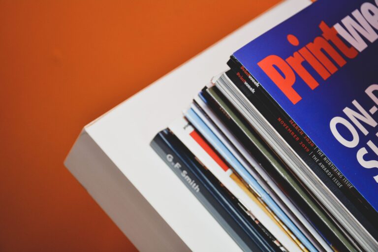 Stack of print magazines on a white desk