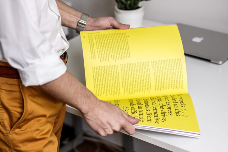 Man's arms with rolled up sleeves holding open a printed magazine