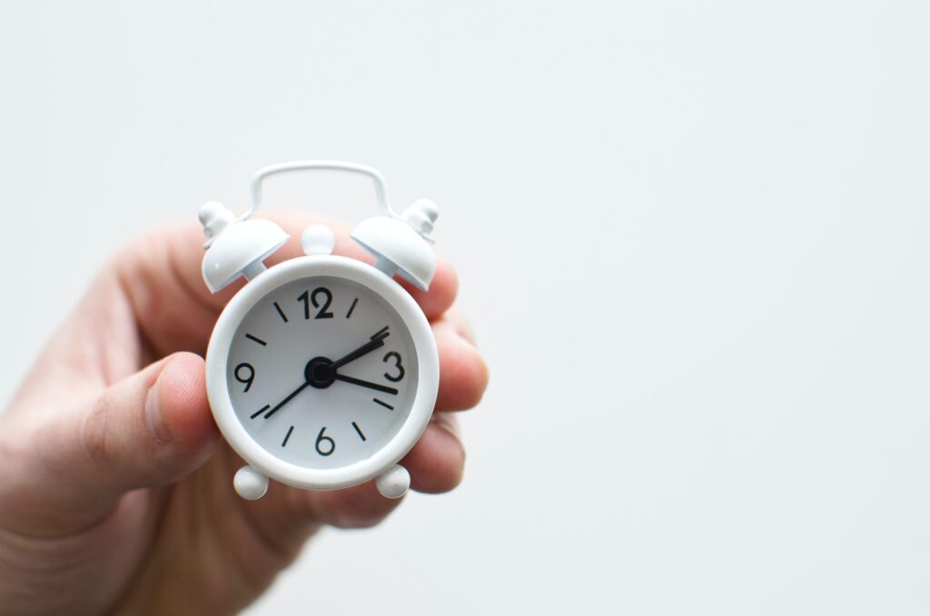 Hand holding a small white alarm clock