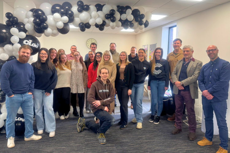 Image: Team photograph of all the staff at Clone Media, stood under a balloon arch