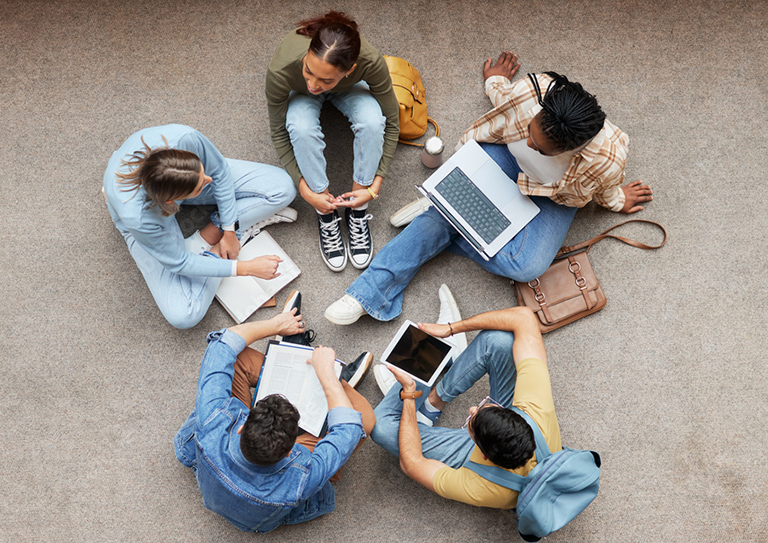 Image: Young people sat in a cirlcle, with a laptop and note book taken from above.